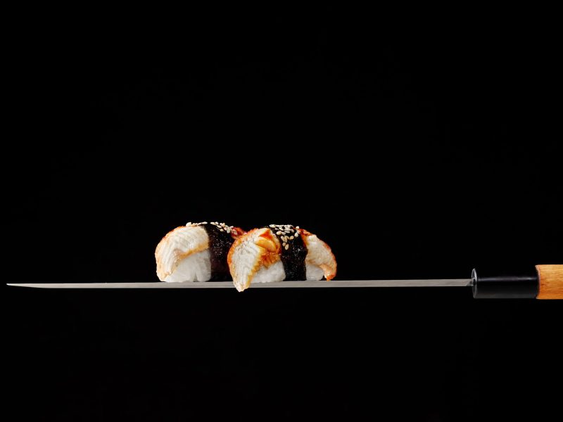 nigiri-sushi-with-eel-served-blade-traditional-japanese-knife-black-background